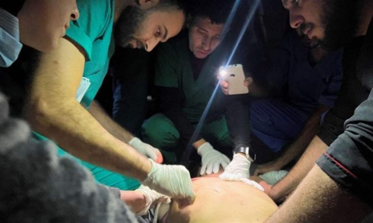 بالصور- الطواقم الطبية تعمل على ضوء الهاتف المحمول في غزة