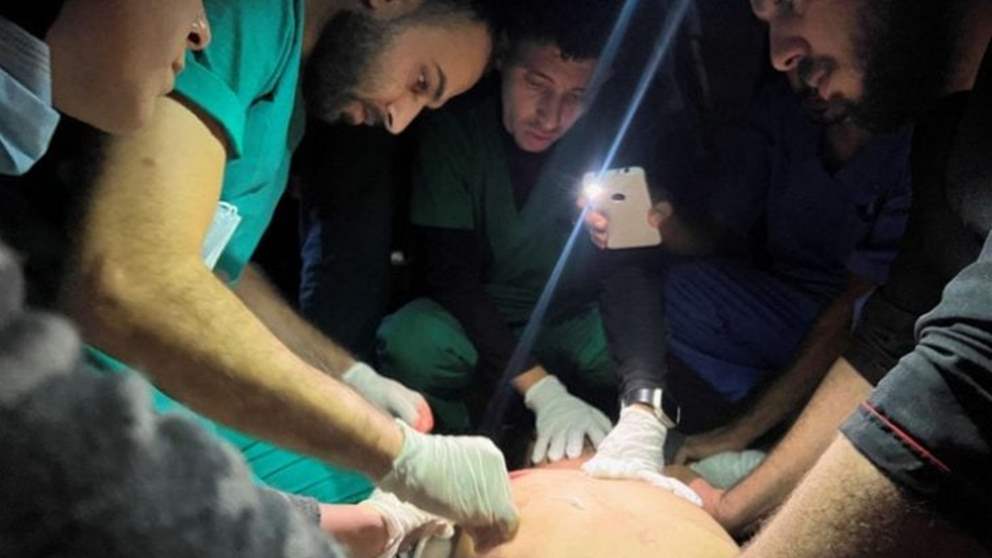 بالصور- الطواقم الطبية تعمل على ضوء الهاتف المحمول في غزة