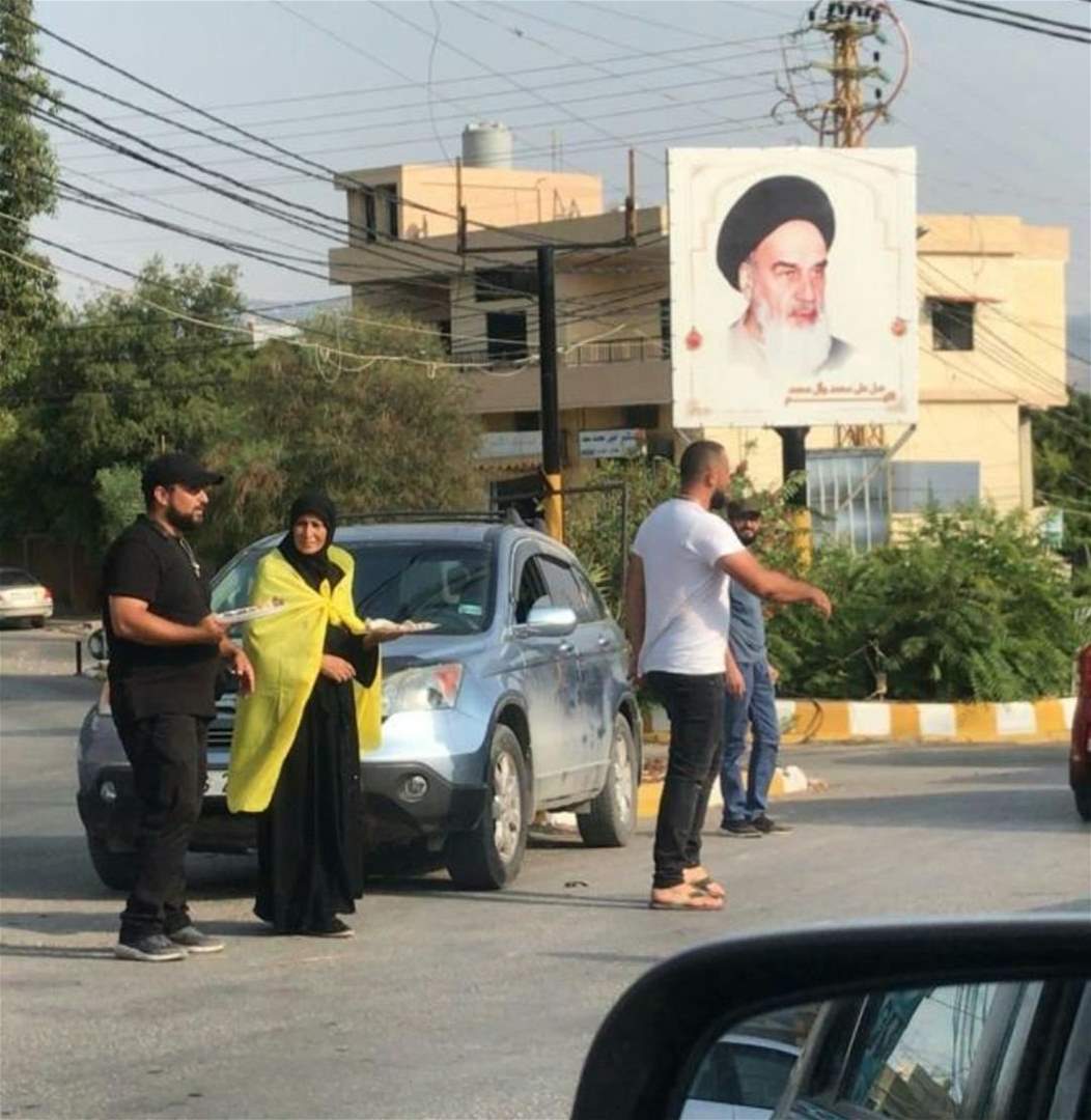 بالصور- والدة الشهيد علي محسن توزّع الحلوى على المارة