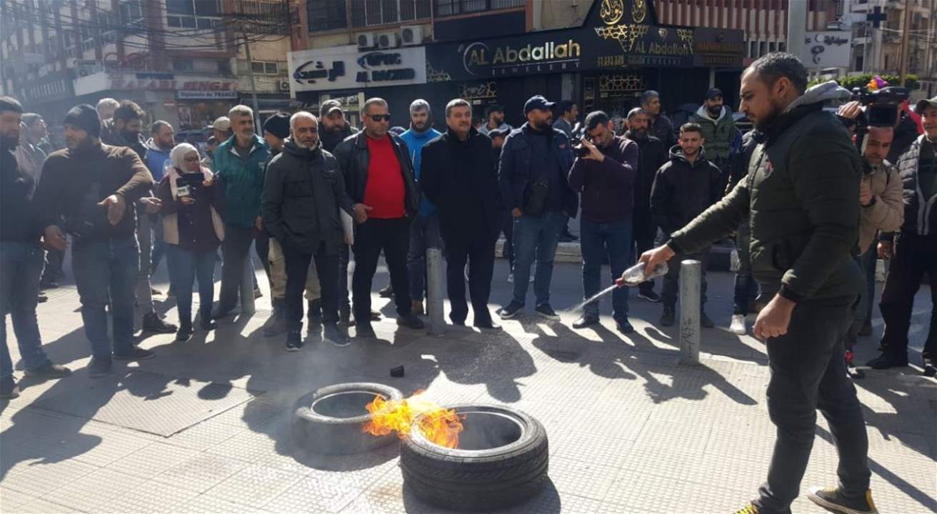 في طرابلس.. عمال البلدية يشعلون الإطارات أمام أحد المصارف في المدينة